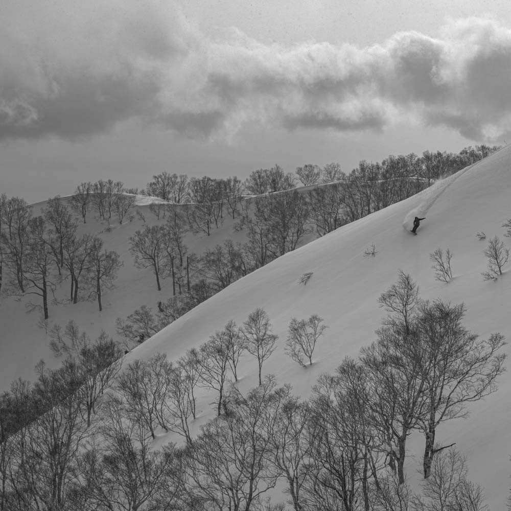 Black and white image of Keisuke Yoshida snowboarding.